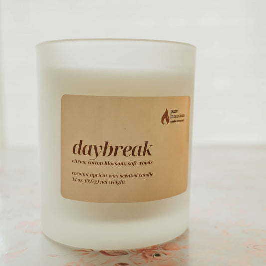 Candle labeled 'daybreak' on a white surface with a light background