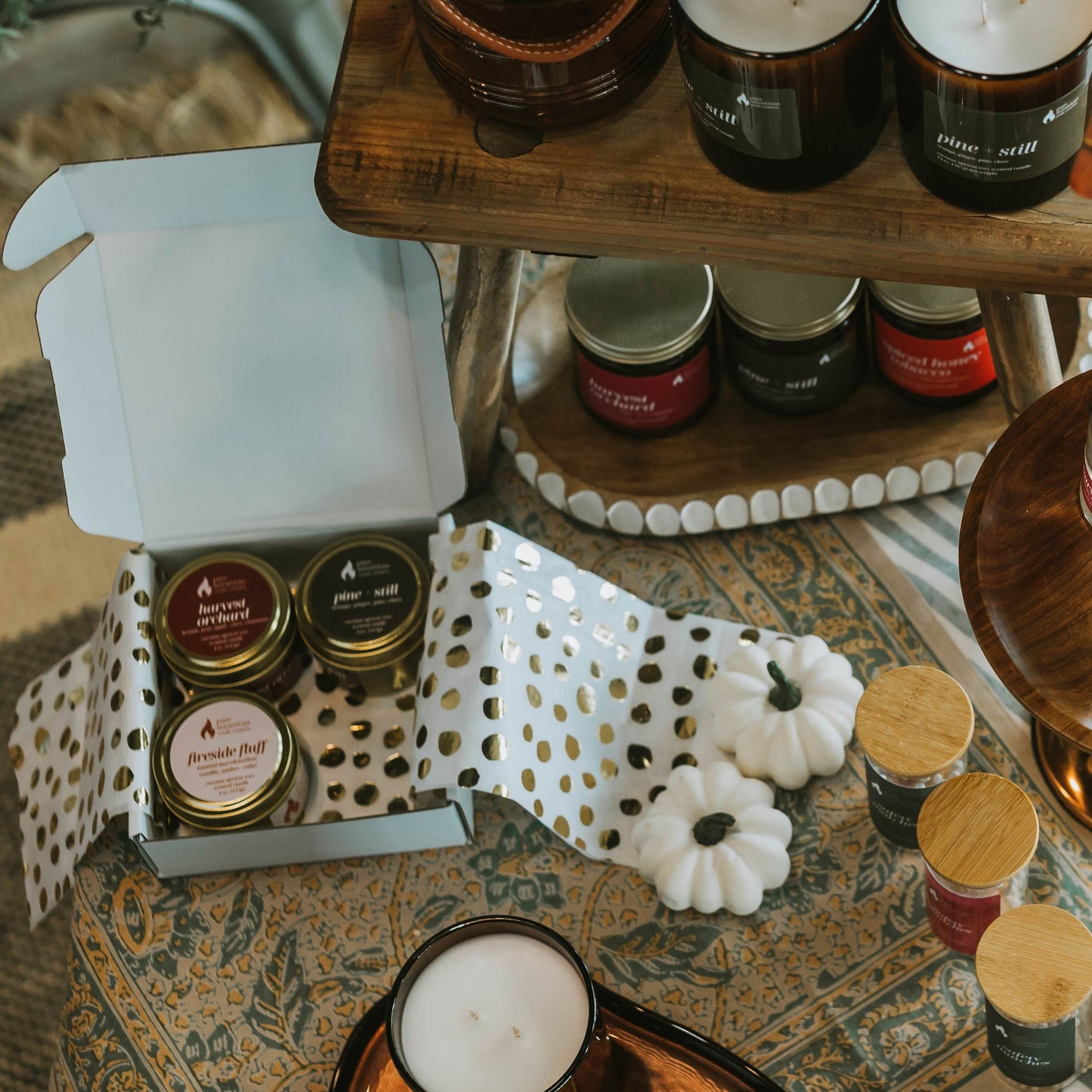 Candles and decorative items on a wooden shelf with a rustic setting.