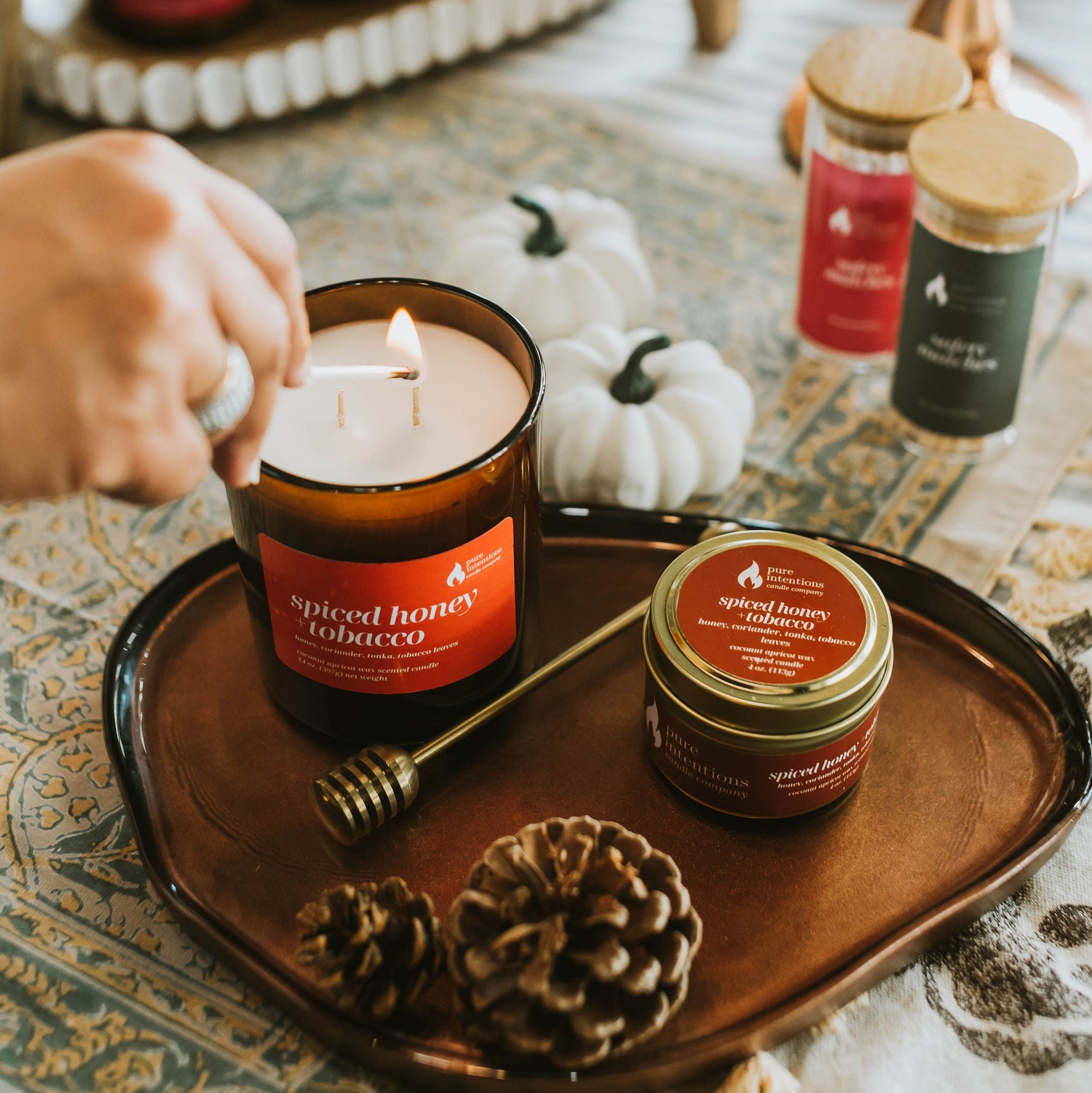 Candle with 'Spiced Honey Tobacco' label on a tray with decorative items.