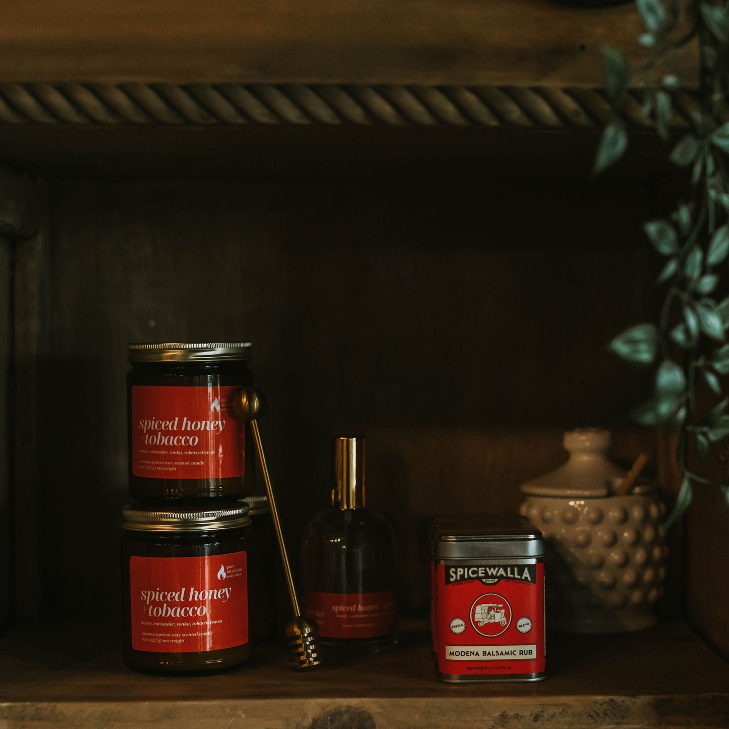 Spicewalla spice jars on a wooden shelf with a plant in the background
