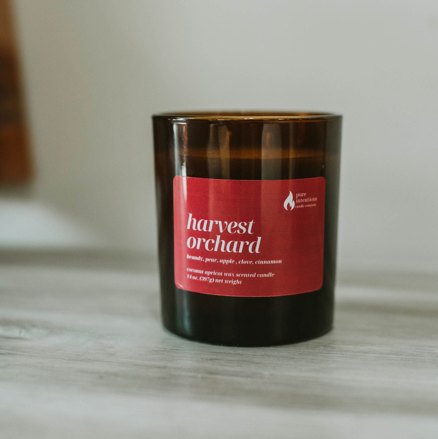 Candle with a red label titled 'Harvest Orchard' on a marble surface.