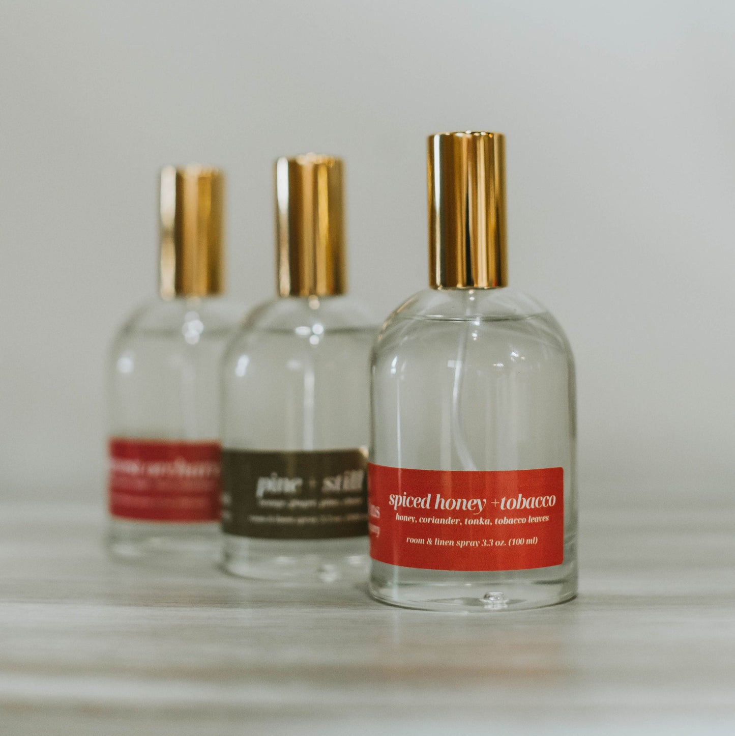 Three perfume bottles with gold caps on a light surface and light gray background