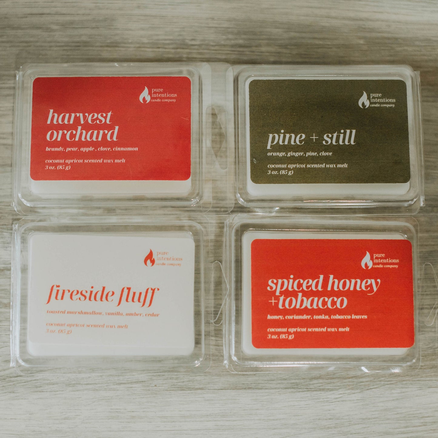 Four wax melt packages with labels on a wooden surface