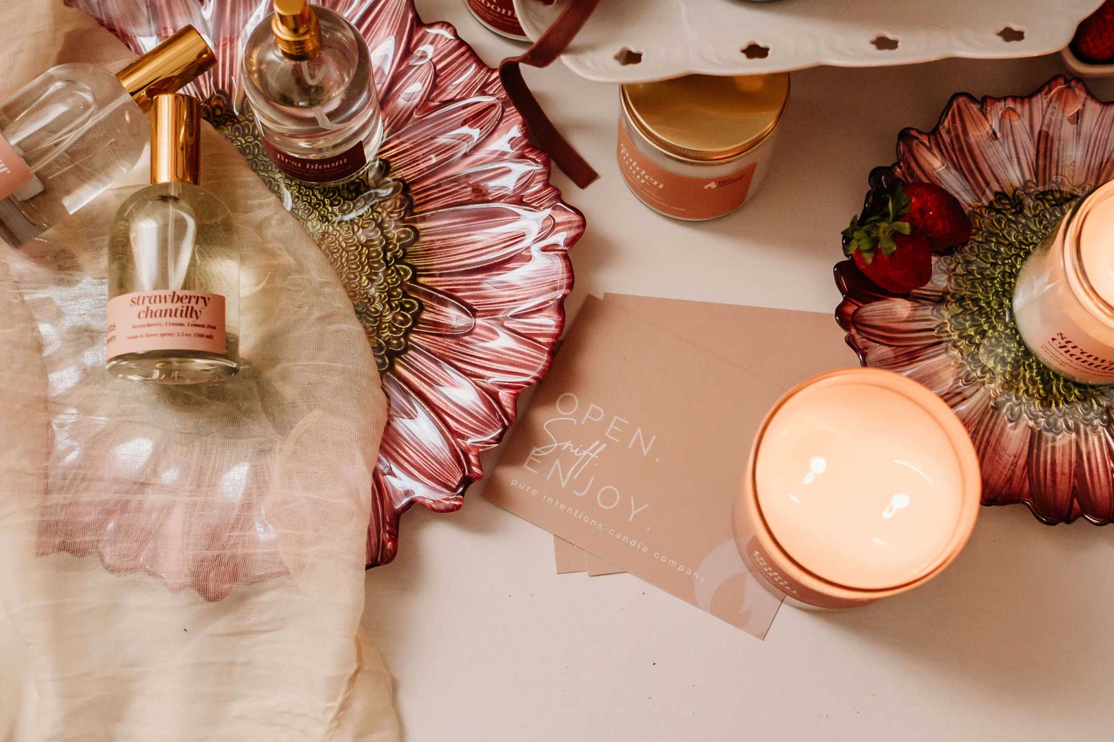 Decorative setup with candles, flowers, and a card on a table.