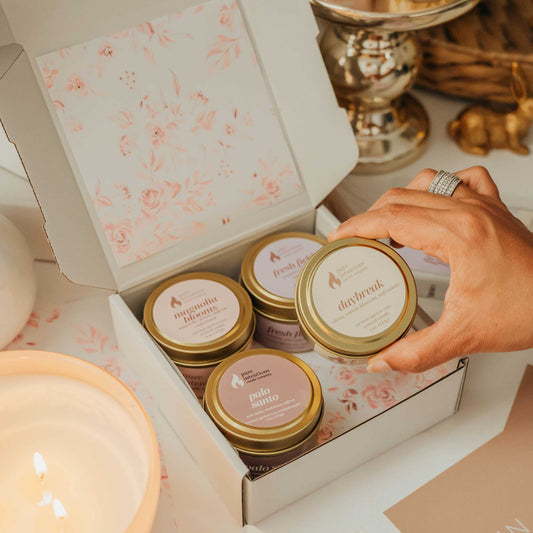Candle packaging with floral design and a hand selecting a candle.
