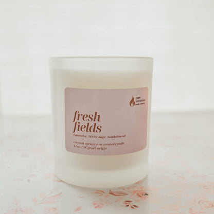 Candle with a 'fresh fields' label on a light background