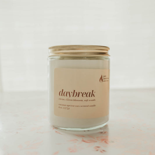 Candle jar labeled 'daybreak' on a light background
