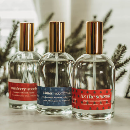Three perfume bottles on a table with Christmas decorations in the background