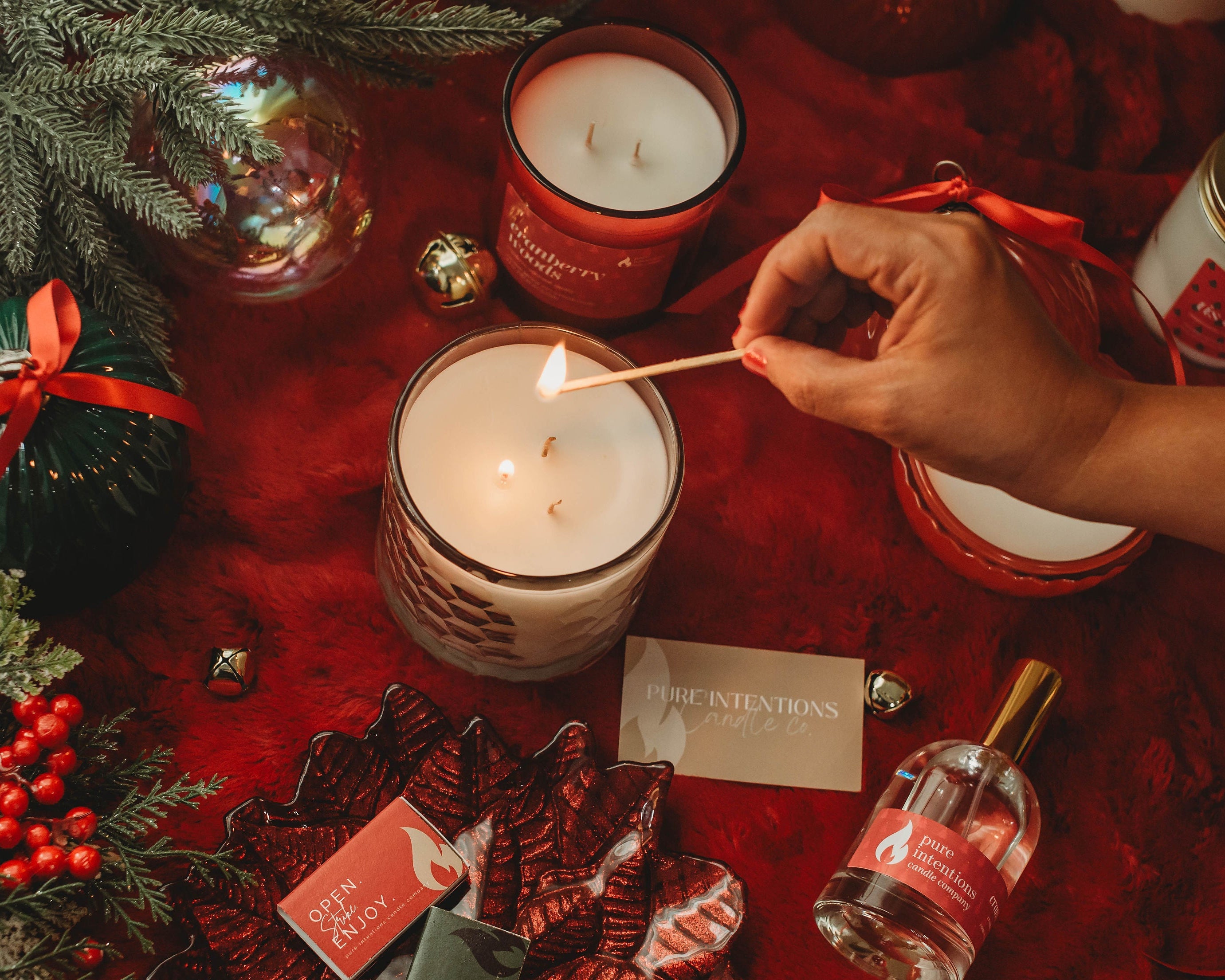 Person lighting a candle on a festive table with Christmas decorations and products.