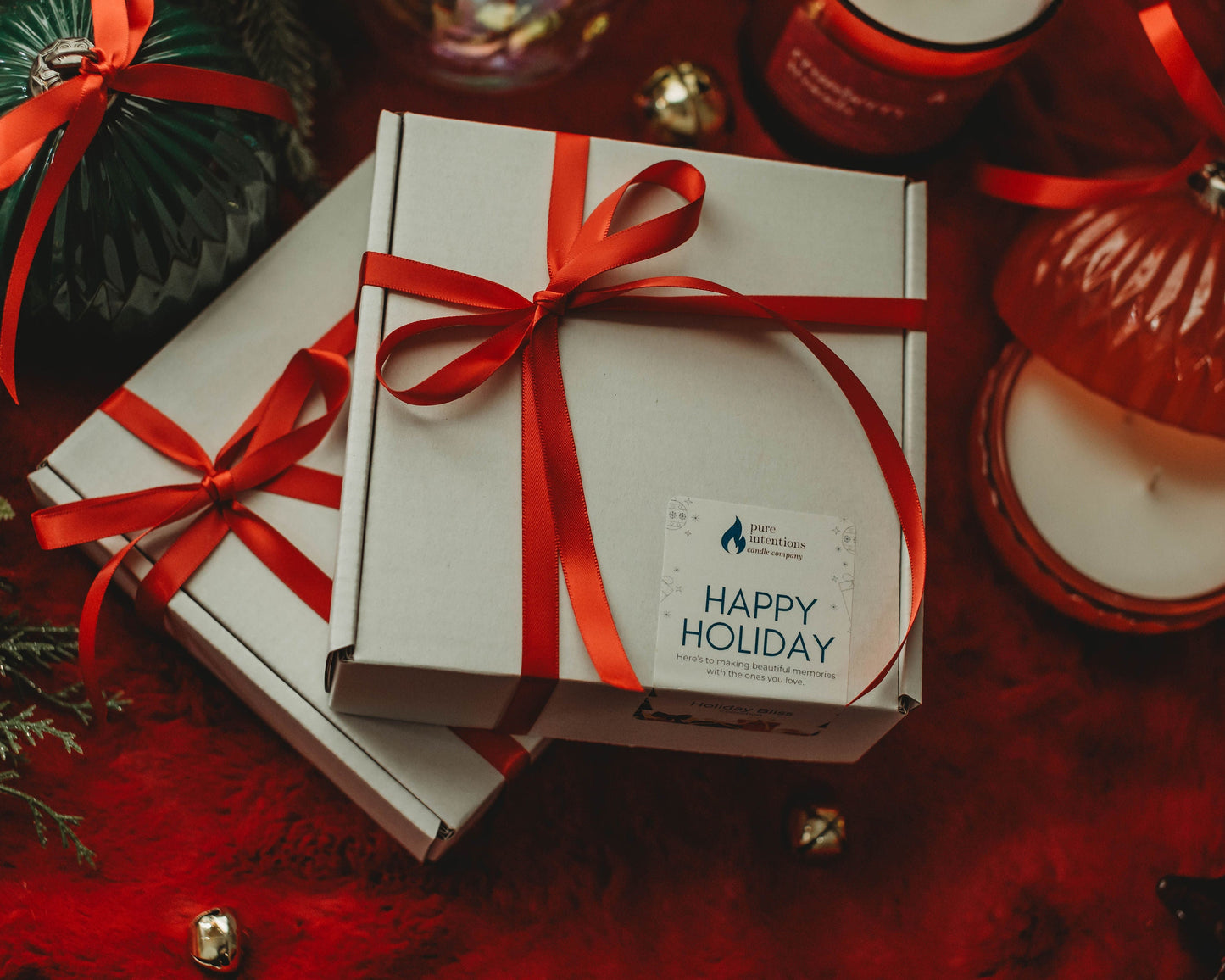 Gift box with red ribbon and 'Happy Holiday' card on a festive background with candles and decorations.