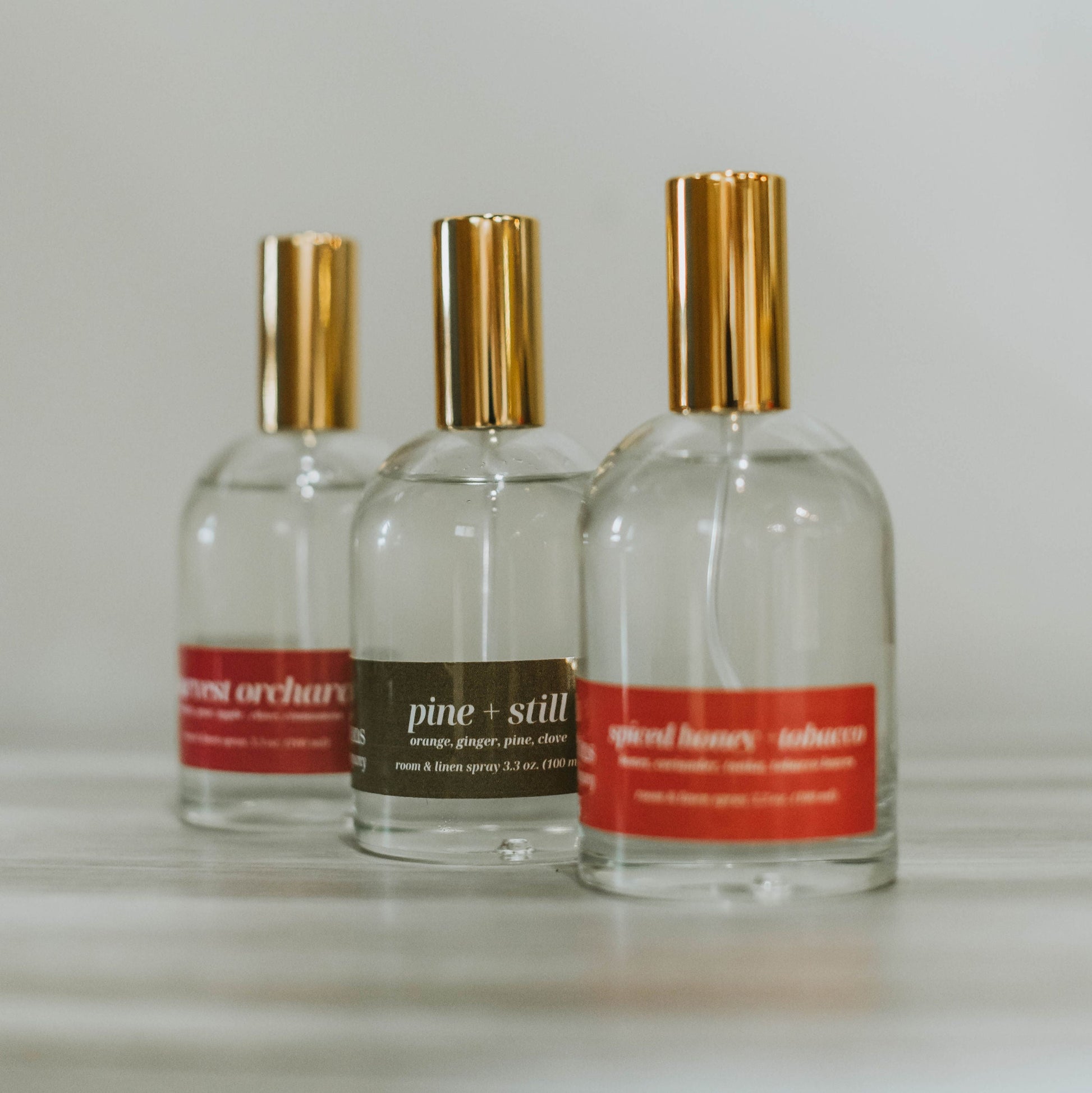 Three bottles of room and linen spray on a light surface with a neutral background