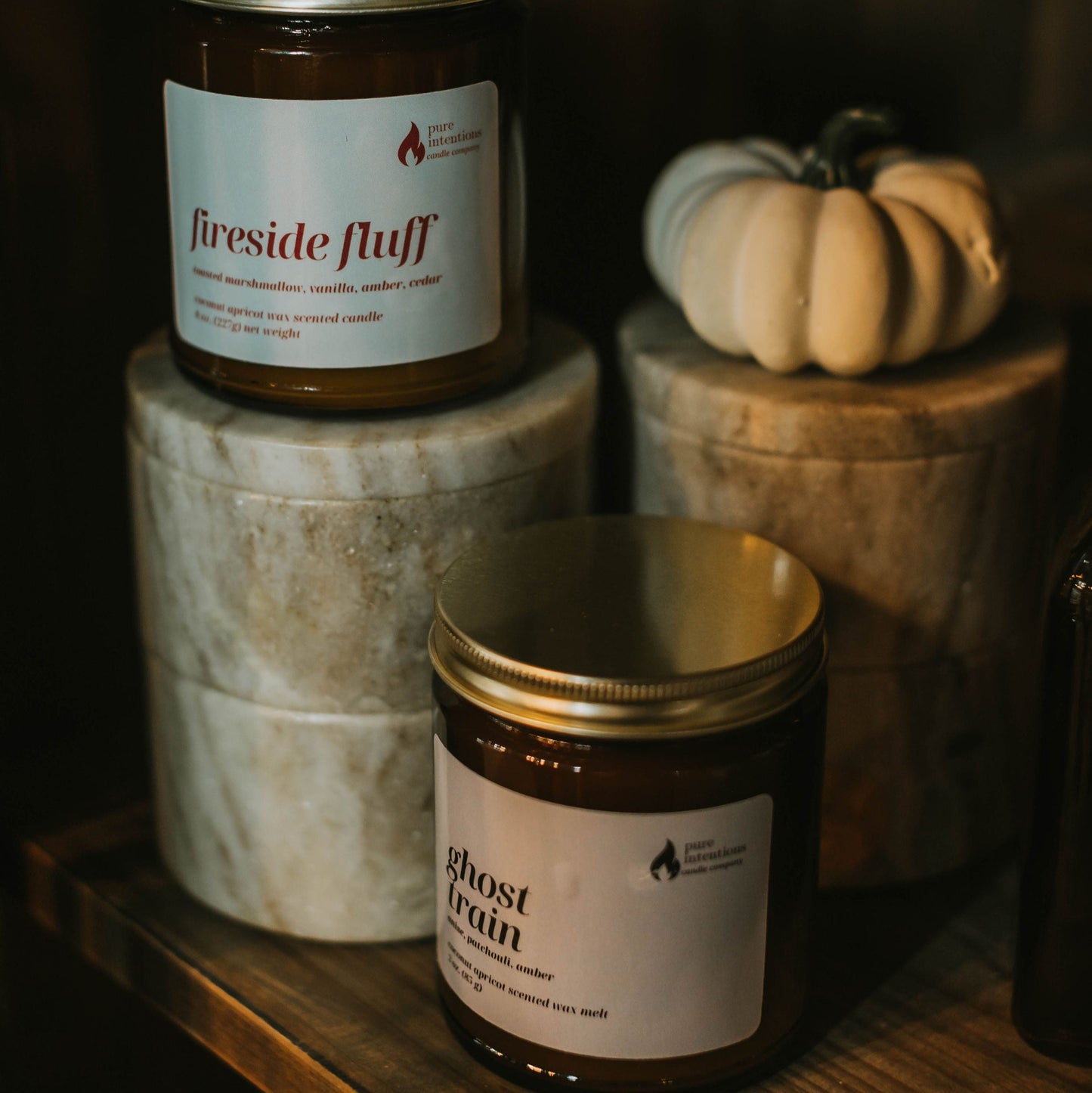 Two jars labeled 'Fireside Fluff' and 'Ghost Rain' on a wooden surface with a dark background.